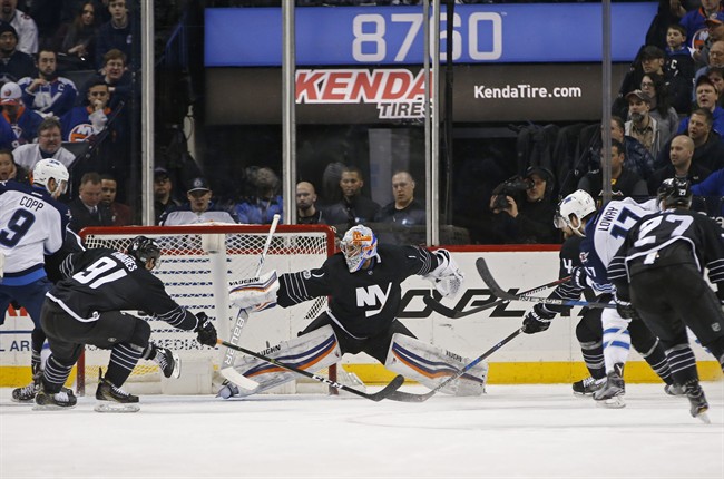 Winnipeg Jets center Adam Lowry scores as the puck sails beyond the reach of New York Islanders goalie Thomas Greiss of Germany with Islanders center John Tavares trying in vain to block it during the second period of an NHL hockey game.