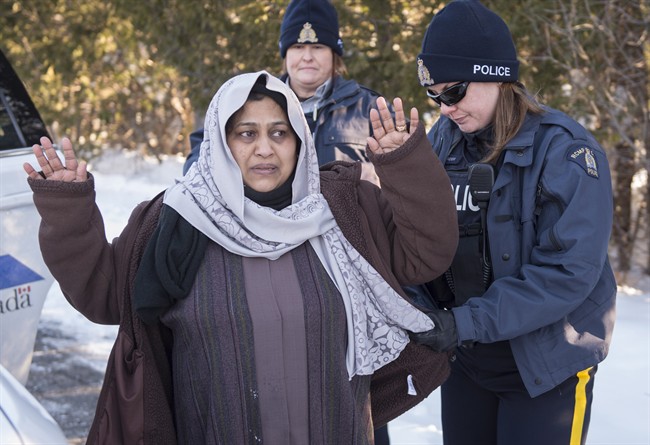 An RCMP officer frisks as asylum claimant after she crossed the border into Canada from the United States with her two daughters, Friday, March 17, 2017 near Hemmingford, Que.