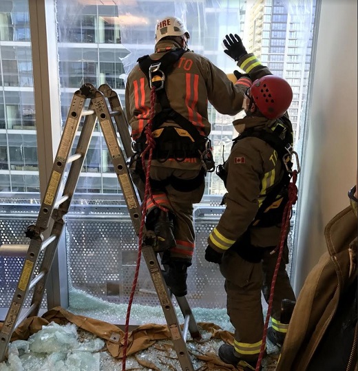 Firefighters break a window to rescue two workers stranded outside of a downtown Toronto office tower Thursday afternoon.