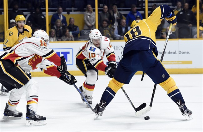 Nashville Predators right wing James Neal (18) passes the puck between his legs away from Calgary Flames right wing Kris Versteeg (10) during the first period of an NHL hockey game Thursday, March 23, 2017, in Nashville, Tenn. 