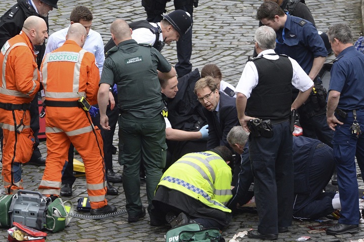 Conservative Member of Parliament Tobias Ellwood, centre, helps emergency services attend to an injured person outside the Houses of Parliament, London, Wednesday, March 22, 2017. London police say they are treating a gun and knife incident at Britain's Parliament "as a terrorist incident until we know otherwise." The Metropolitan Police says in a statement that the incident is ongoing. It is urging people to stay away from the area. Officials say a man with a knife attacked a police officer at Parliament and was shot by officers. Nearby, witnesses say a vehicle struck several people on the Westminster Bridge.
