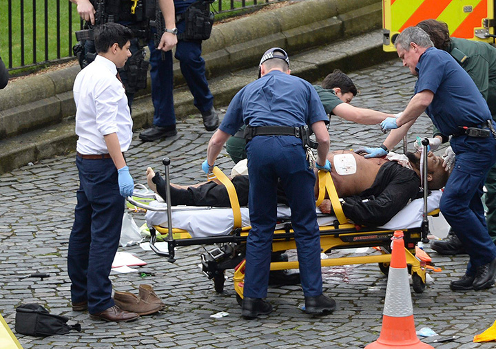 A man is treated by emergency services, as a knife lies on the ground, with police looking on at the scene outside the Houses of Parliament London, Wednesday, March 22, 2017.