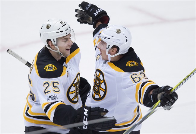 Boston Bruins defenceman Brandon Carlo (25) and left wing Brad Marchand (63) celebrate Marchand's second goal against the Vancouver Canucks during the third period of an NHL hockey game in Vancouver, B.C., on Monday March 13, 2017.