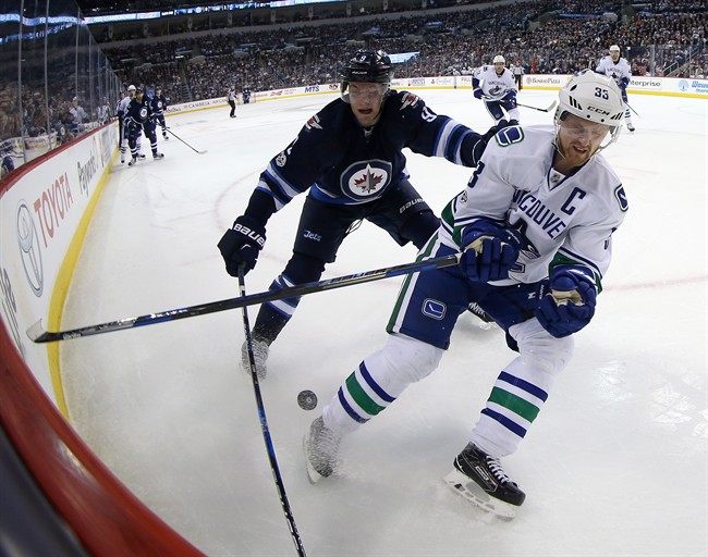 Winnipeg Jets' Andrew Copp (9) battles Vancouver Canucks' Henrik Sedin (33) during second period NHL hockey action in Winnipeg, Sunday, March 26, 2017. 