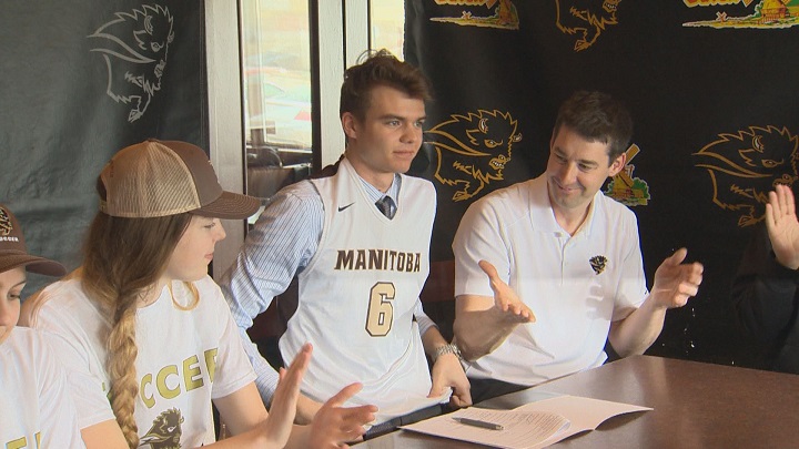 New Manitoba Bisons basketball recruit Wyatt Tait puts on his Bisons jersey after signing his letter of intent.