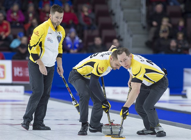 Manitoba skip Mike McEwen, left, follows as Matt Wozniak and Denni Neufeld, right, sweep against Northern Ontario in bronze medal action at the Tim Hortons Brier curling championship at Mile One Centre in St. John's on Sunday, March 12, 2017. 