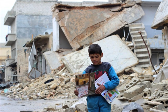 In this picture taken in January 2017 and provided by UNICEF, a child carries manuals distributed by UNICEF volunteers in the area following an informative session on identifying and reporting unexploded object, at Al- Sakhoor neighbourhood, east Aleppo, Syria. The U.N.'s child relief agency says at least 652 children were killed in Syria last year, making 2016 the worst year yet for the country's rising generation. UNICEF says schools, hospitals, playgrounds, parks, and homes across the country are unsafe for children and come frequently under attack. (Khudr Al-Issa/ UNICEF via AP ).