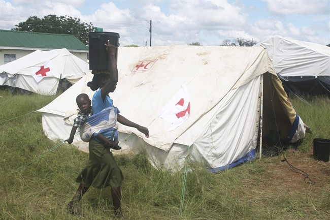 A woman and her baby walk past a tent in Tsholotsho after she was rescued following floods in this Friday, Feb. 24, 2017 photo made available by UNICEF Zimbabwe. Zimbabwe says floods have killed 246 people and left 2,000 homeless since December. The Southern African country has appealed to International donors for $100 million to help those affected by floods.(UNICEF via AP).