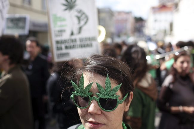 A young woman wears sunglasses in the shape of cannabis leaves while taking part in a march celebrating cannabis culture May 7 2011, in Lisbon, Portugal.
