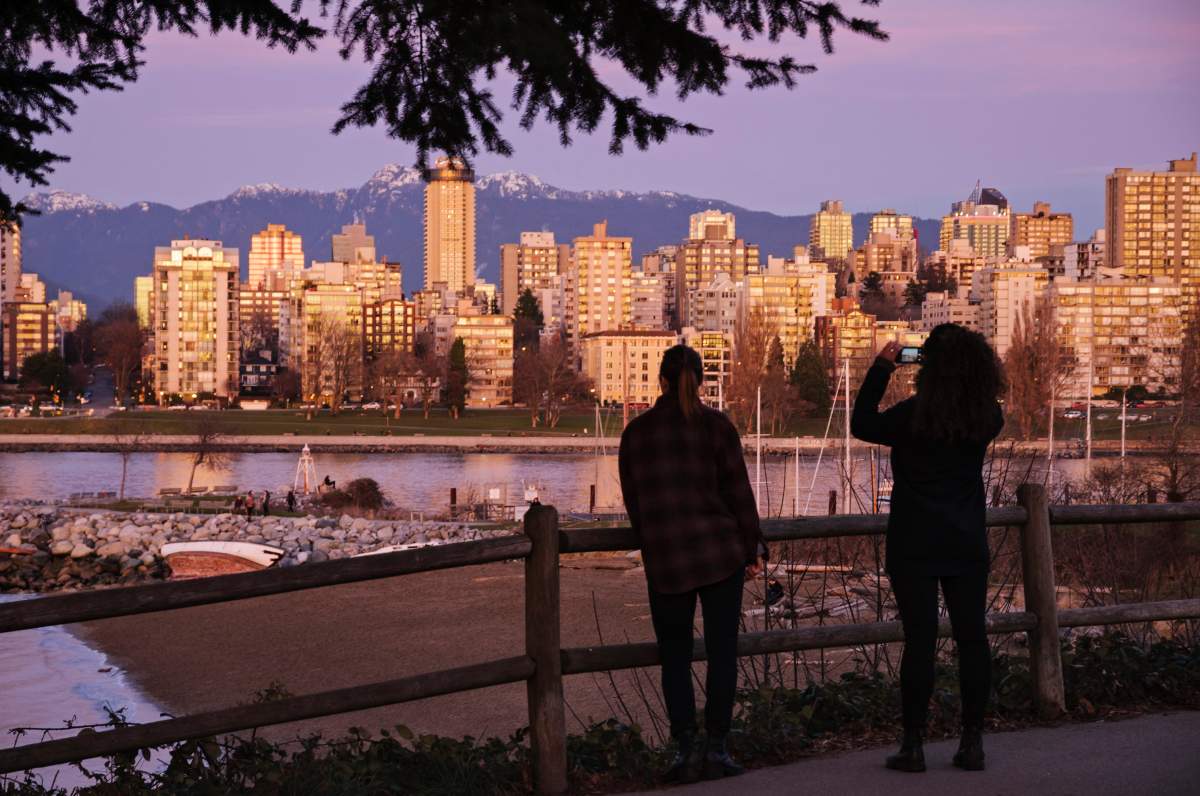 Two women on Kits Point stop to admire the Vancouver skyline; one captures the scene on her smartphone, Jan. 5, 2014.