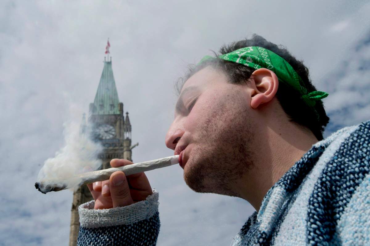 A man is shown smoking a joint at the Fill the Hill marijuana rally on Parliament Hill in Ottawa on Sunday, April 20, 2014.