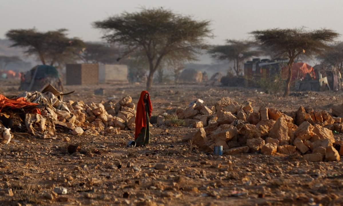 A Somali woman walks through a camp of people displaced from their homes elsewhere in the country by the drought, shortly after dawn in Qardho, Somalia Thursday, March 9, 2017.