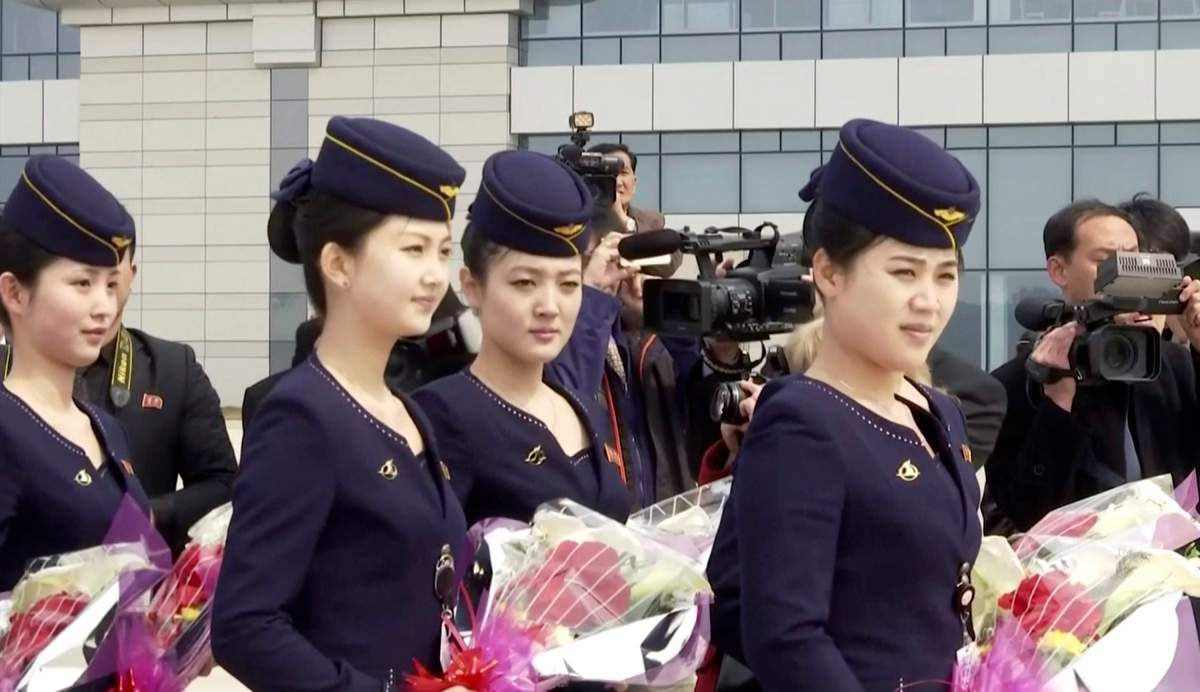 In this image taken from video, Air Koryo cabin crew wait with flowers on tarmac for the airline’s first flight from Dandong, at Sunan airport in Pyongyang, North Korea on Tuesday, March 28, 2017.