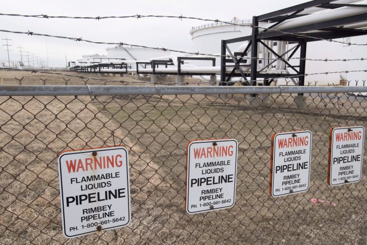 Pipes and tanks are seen behind a barbed wire fence at the Kinder Morgan Trans Mountain facility in Edmonton, Alta.