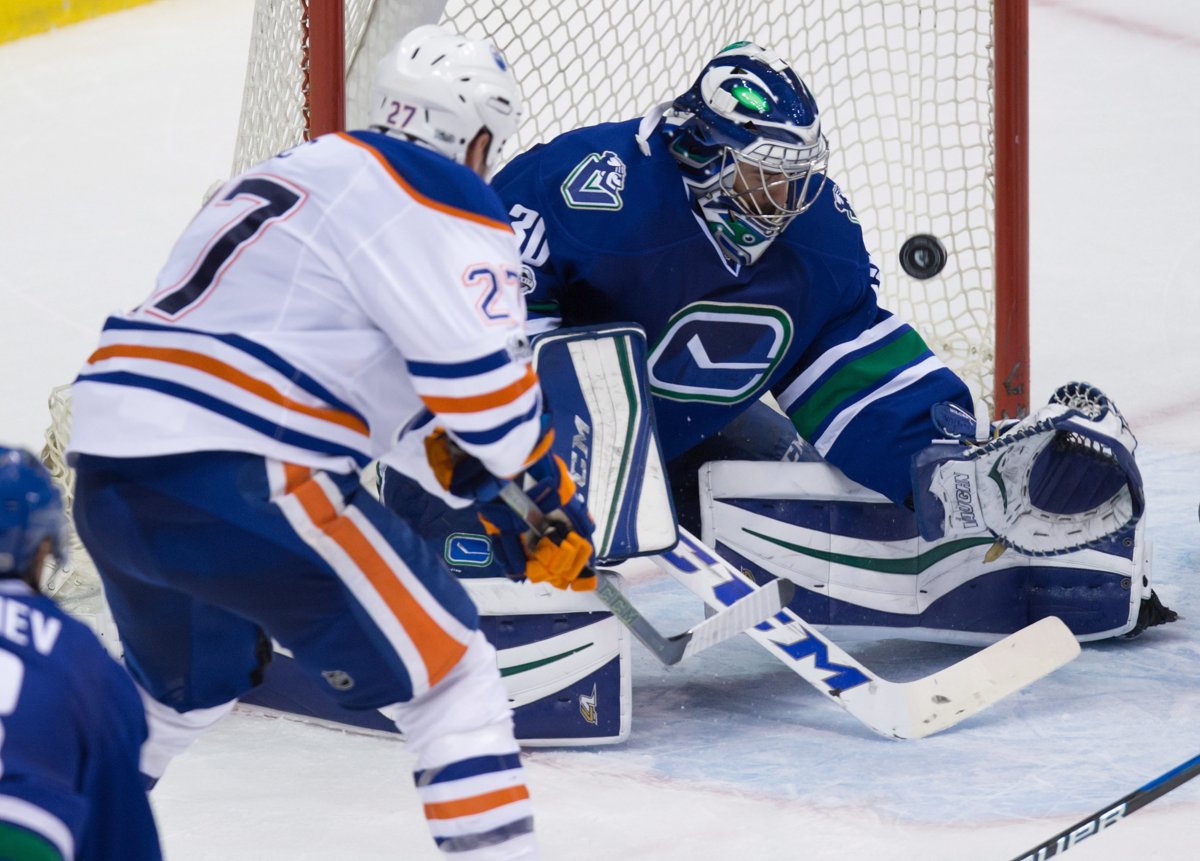 Edmonton Oilers' Milan Lucic, left, puts a shot over the net behind Vancouver Canucks goalie Ryan Miller during second period NHL hockey action in Vancouver, B.C., on Saturday, April 8, 2017. THE CANADIAN PRESS/Darryl Dyck.