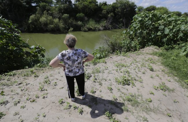 Pamela Taylor, whose home is on the south side of the border fence, stands near the Rio Grande, in Brownsville, Texas. 

