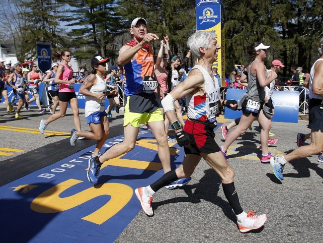 Leeland Cole-Chu (15537) identifies Ben Beach, center, as he crosses the start line running his 50th consecutive Boston Marathon at the start of the race in Hopkinton, Mass., Monday, April 17, 2017.