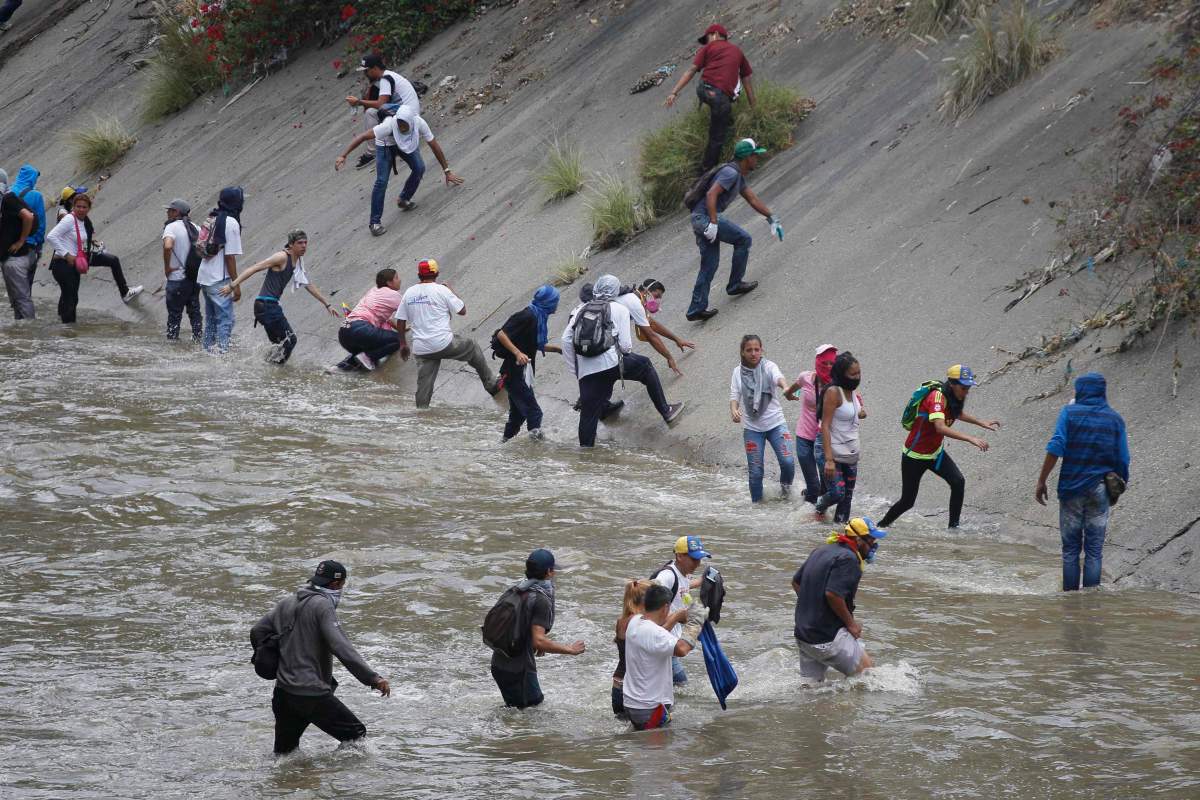 Demonstrators wade across the Guaire River as they run away from security forces during anti-government protests in Caracas, Venezuela, Wednesday, April 19, 2017. Tens of thousands of opponents of President Nicolas Maduro flooded the streets of Caracas in what’s been dubbed the “mother of all marches” against the embattled president. (AP Photo/Ariana Cubillos)