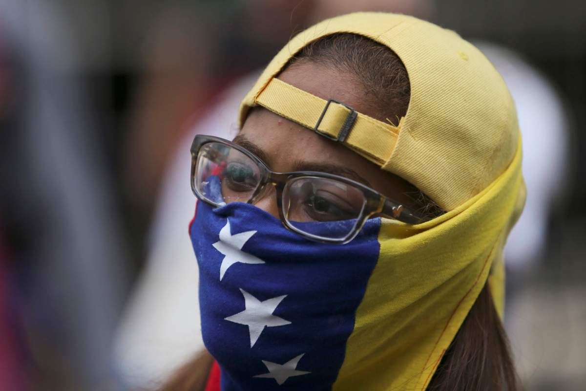 A demonstrator covers her face with a Venezuelan flag as she stands at a barricade during anti-government protests in Caracas, Venezuela, Wednesday, April 19, 2017. Tens of thousands of opponents of President Nicolas Maduro flooded the streets of Caracas in what’s been dubbed the “mother of all marches” against the embattled president. (AP Photo/Fernando Llano)