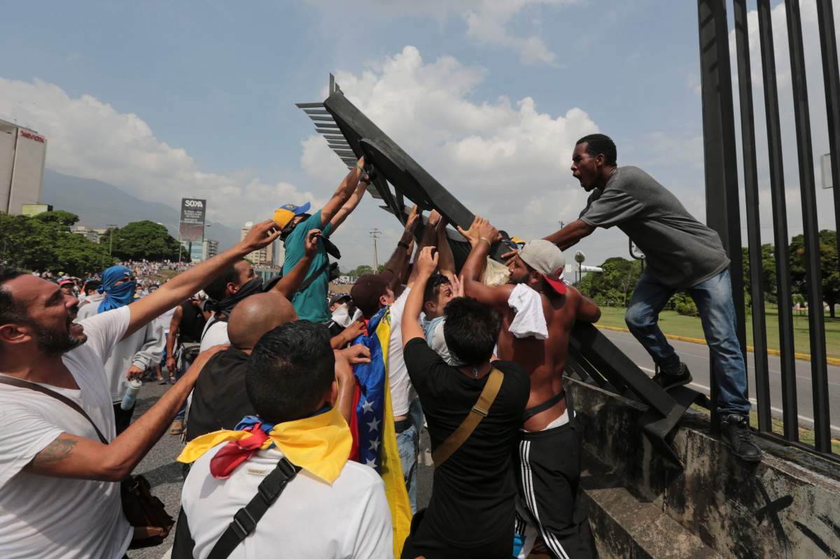 Anti-government protesters bring down a fence to set up barricades in Caracas, Venezuela, Wednesday, April 19, 2017. Tens of thousands of opponents of President Nicolas Maduro flooded the streets of Caracas in what’s been dubbed the “mother of all marches” against the embattled president. (AP Photo/Fernando Llano)