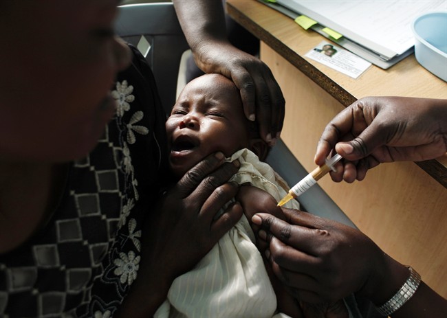 FILE - In this Oct. 30, 2009, file photo, a mother holds her baby receiving a new malaria vaccine as part of a trial at the Walter Reed Project Research Center in Kombewa in Western Kenya. 