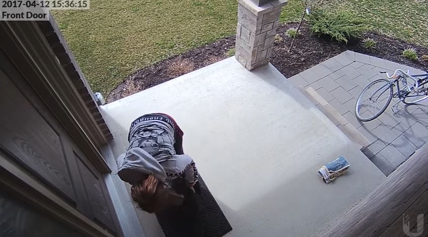A still from a YouTube video appears to show a woman taking a package from the front steps of a London home.
