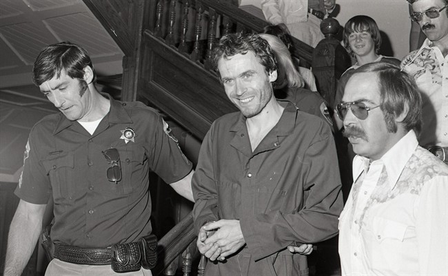 In this 1977 photo, serial killer Ted Bundy, centre, is escorted out of court in Pitkin County, Colo.
