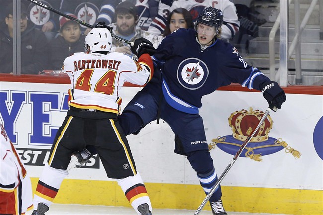 Calgary Flames' Matt Bartkowski (44) checks Winnipeg Jets' Patrik Laine (29) during first period NHL action in Winnipeg on Saturday, March 11, 2017. 