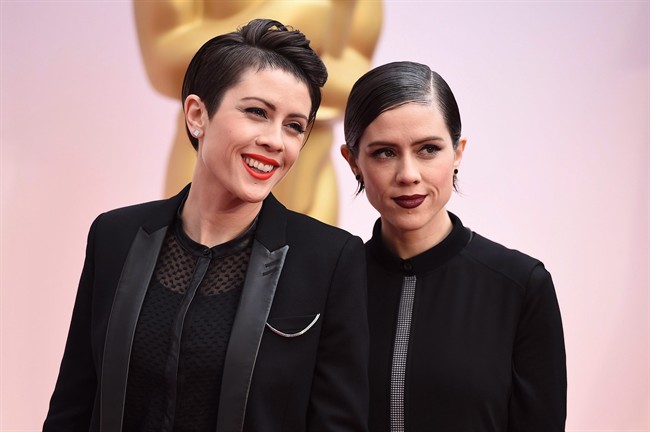 Tegan Quin, left, and Sara Quin of the musical group Tegan and Sara arrive at the Oscars on Sunday, Feb. 22, 2015, at the Dolby Theatre in Los Angeles. Twin sisters Tegan and Sara are putting their names behind social causes in a bigger way than ever this year.