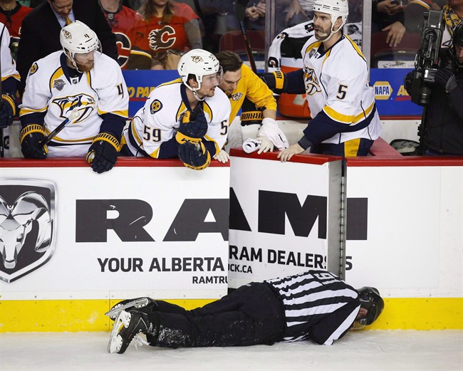 Nashville Predators' players look over the bench at linesman Don Henderson after he was hit by Calgary Flames' Dennis Wideman during second period NHL hockey action in Calgary, Wednesday, Jan. 27, 2016.