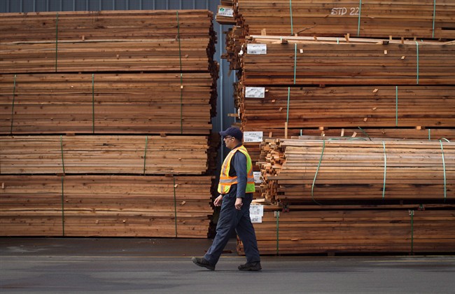 A worker walks past stacks of lumber at the Partap Forest Products mill in Maple Ridge, B.C., on Tuesday April 25, 2017. A hefty American tariff on Canadian softwood could be devastating for British Columbia's economy, but it may also be advantageous for political leaders on the campaign trail who are looking to cement or build their images with voters, says a former premier. 