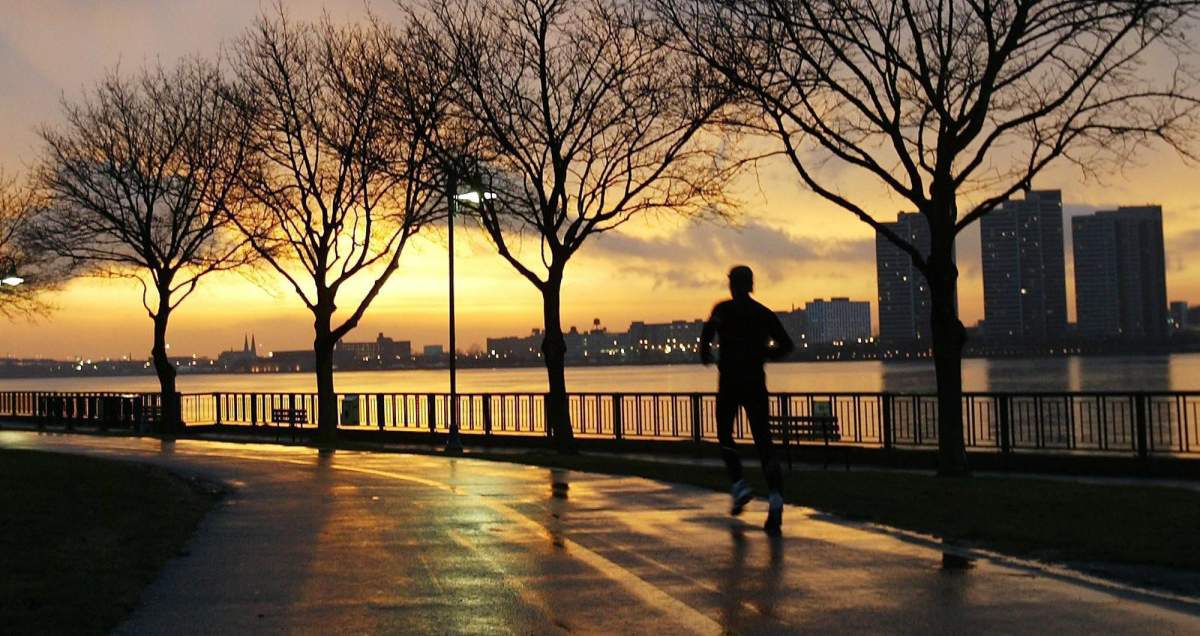 A man jogs along Windsor, Ont.’s riverfront as the sun sets over the Detroit skyline, on March 29, 2004.