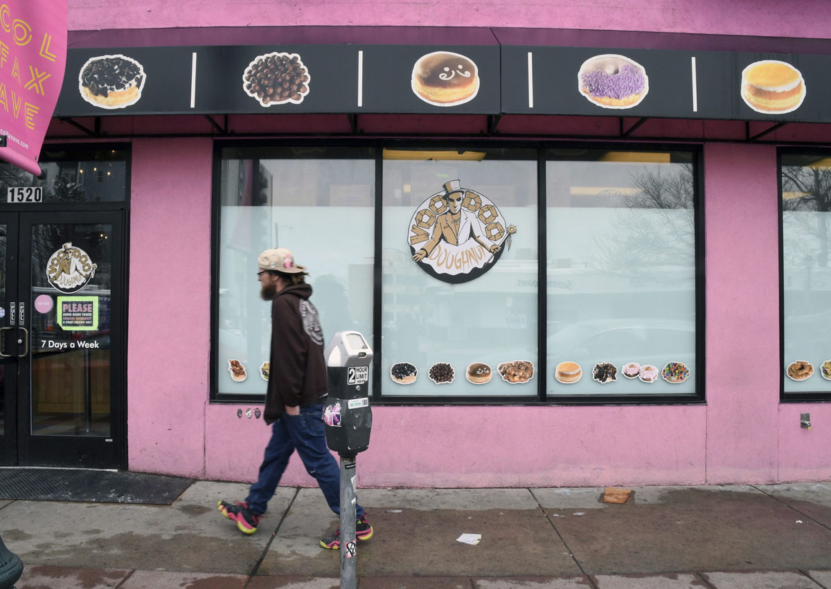A man walks past the storefront of Voodoo Doughnuts on East Colfax Avenue in Denver on Tuesday, April 4, 2017. (AP Photo/Thomas Peipert)