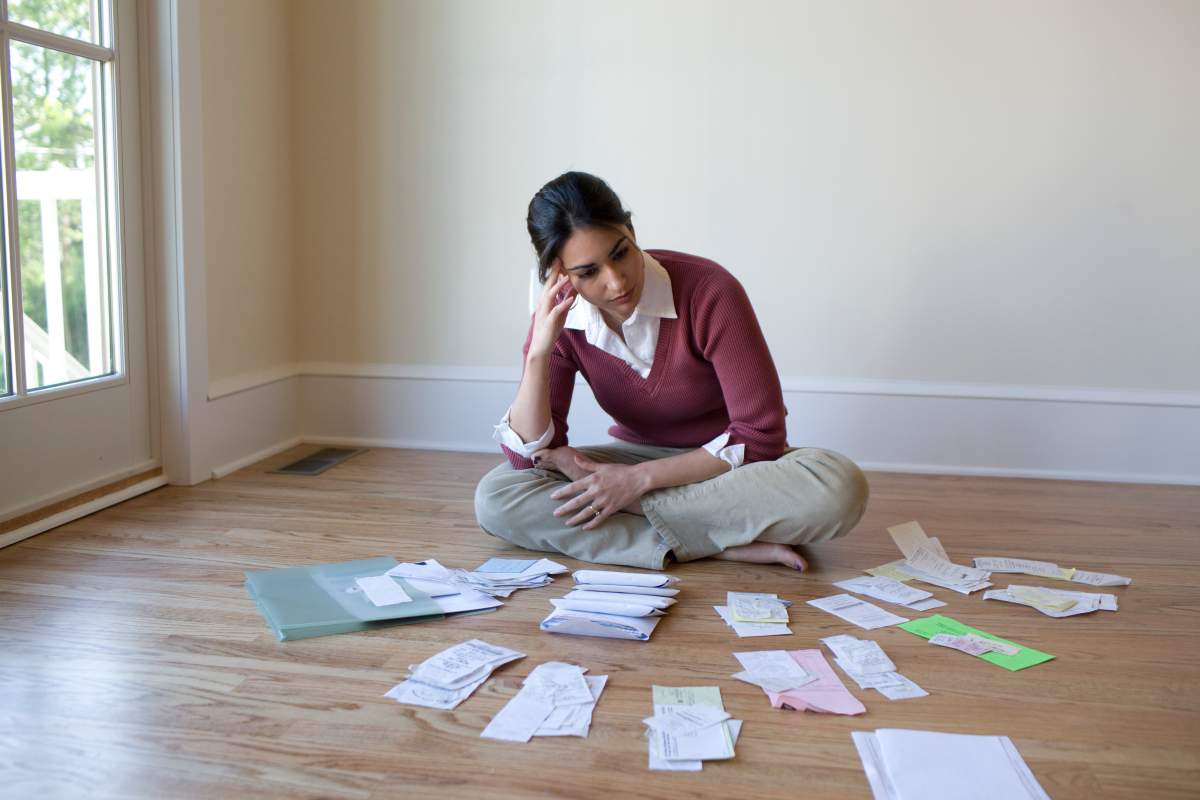 Woman looking at bills and receipts on floor.