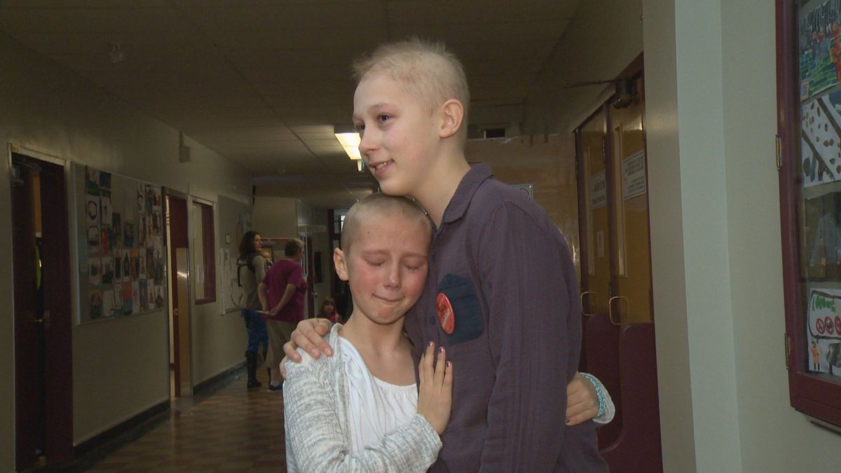 Sofia Smith hugs her brother Rand after raising $20K by shaving her head for Kids Cancer Care.
