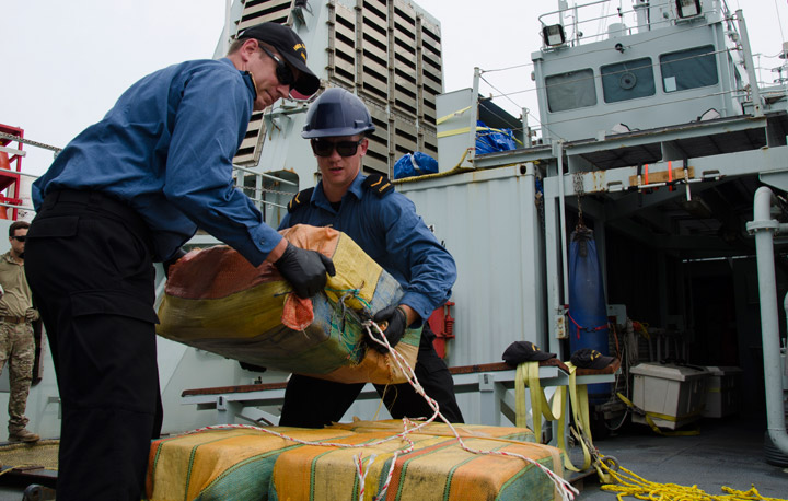 The executive officer of Her Majesty’s Canadian Ship Saskatoon, Lt. (Navy) Christopher Shook and a crewmember move bales of cocaine into a net for transfer to United States Coast Guard custody on April 8, 2017 after an interdiction on April 6, 2017 during Operation Caribbe.