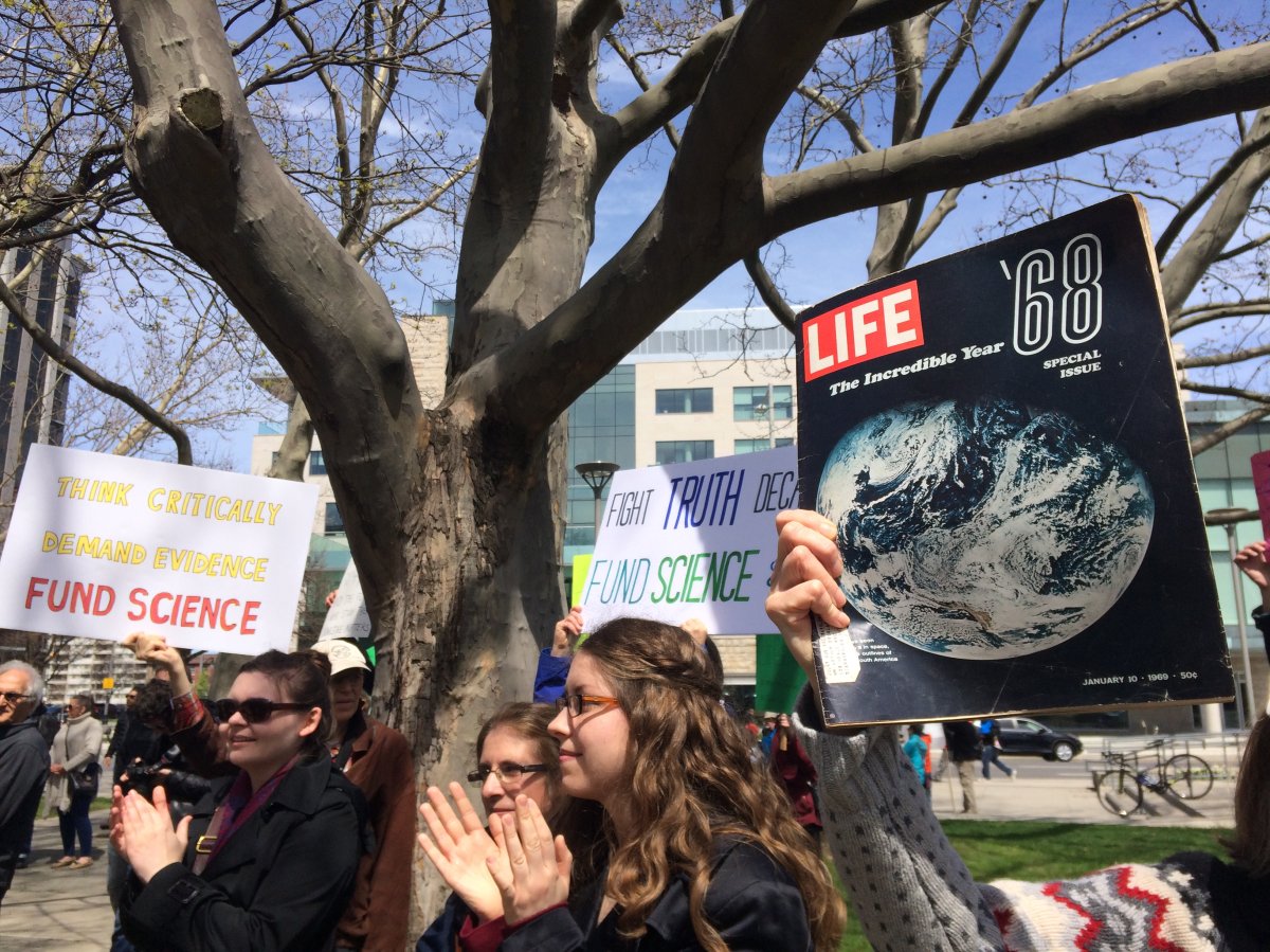 Science enthusiasts hold up signs at Saturday's March For Science at Hamilton City Hall.