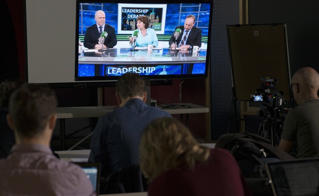 Reporters watch the British Columbia election leadership live radio debate with NDP Leader John Horgan, Liberal Leader Christy Clark and Green Party Leader Andrew Weaver on a television in Vancouver, Thursday, April 20, 2017.