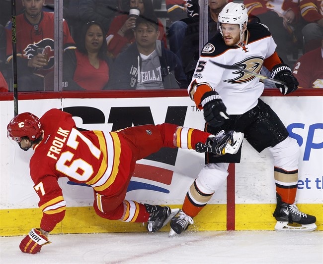 Anaheim Ducks' Korbinian Holzer, right, from Germany, knocks down Calgary Flames' Michael Frolik, from Czech Republic, during first period NHL action in Calgary, Alta., Sunday, April 2, 2017. 