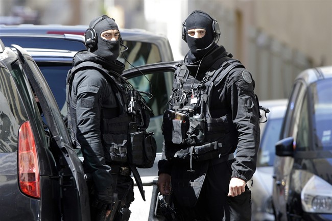 Hooded police officers patrol outside a building during searches in Marseille, southern France, April 18, 2017. 