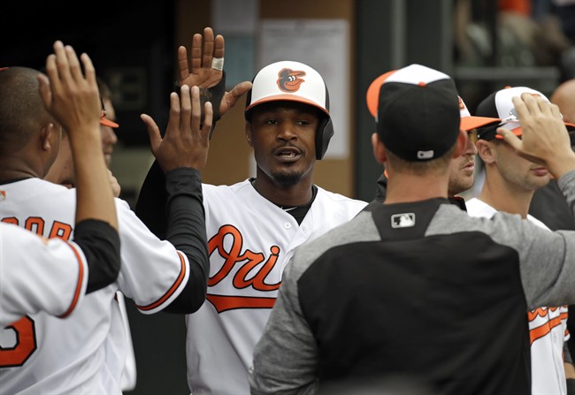 Adam Jones high-fives teammates in the dugout after scoring on a double by Mark Trumbo in the third inning of an opening-day baseball game against the Toronto Blue Jays in Baltimore.