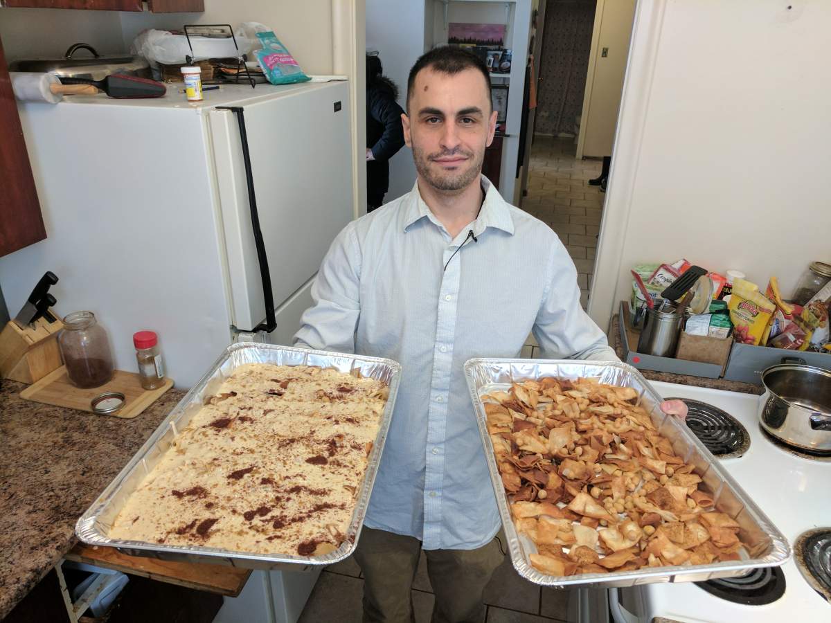 Mohammad Al Jokhadar holds two nearly completed trays of fatteh he helped make in Halifax on April 2, 2017.