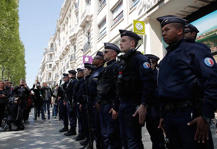 A dozen of police officers stand at attention at the place where a police officer was killed Thursday on the Champs Elysees Boulevard, Friday, April 21, 2017 in Paris.
