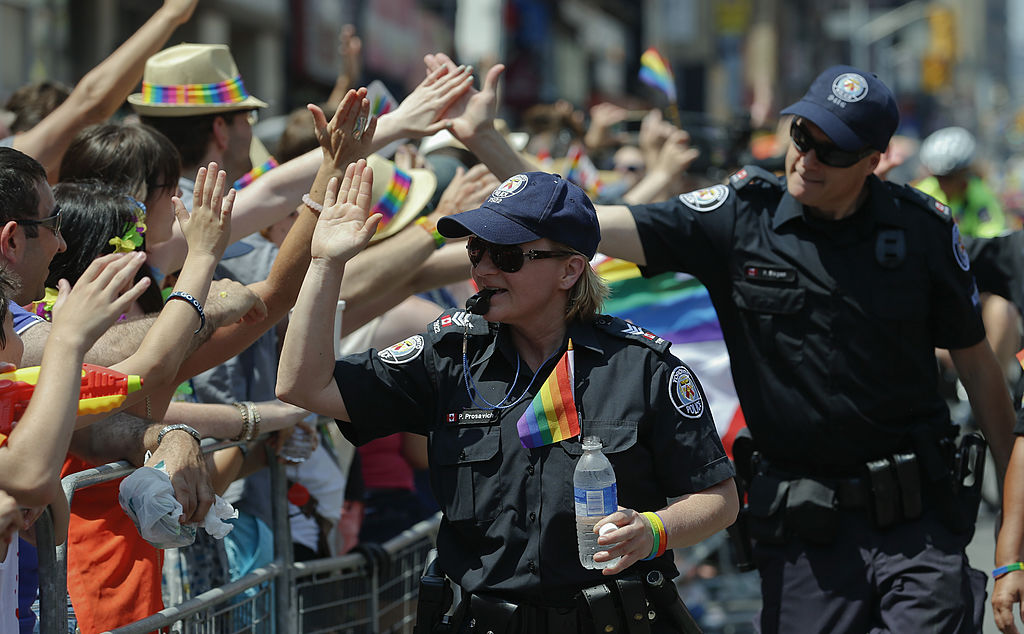 Toronto Police Service personnel marching in the 2014 World Pride Parade in Toronto high-five spectators along the route.