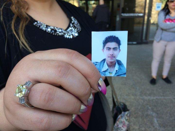 Sarah Hamza holds up picture of her brother Raad Hamza outside the Edmonton Law Courts.