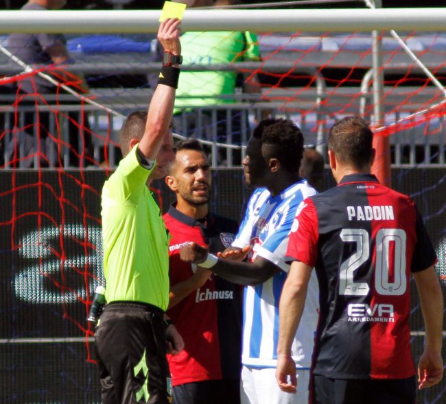 Pescara player Sulley Muntari, second from right, is shown a yellow card after he complained to the referee about racist abuse from fans during a Serie A soccer game at the Cagliari Sant'Elia stadium, Italy, April 30, 2017.

