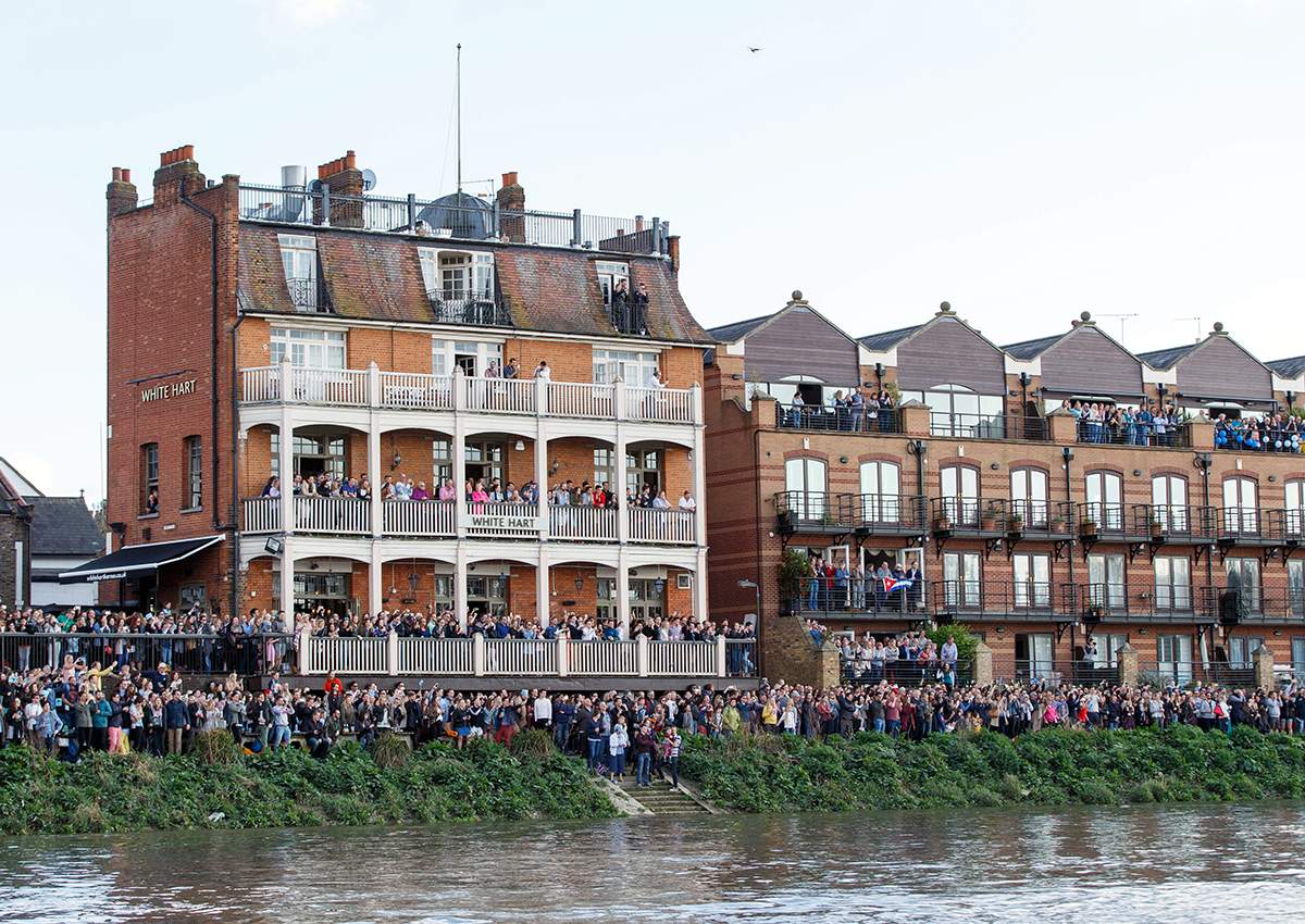 Fans line the river bank during the Cancer Research Boat Race between Oxford University and Cambridge University on the River Thames, London.