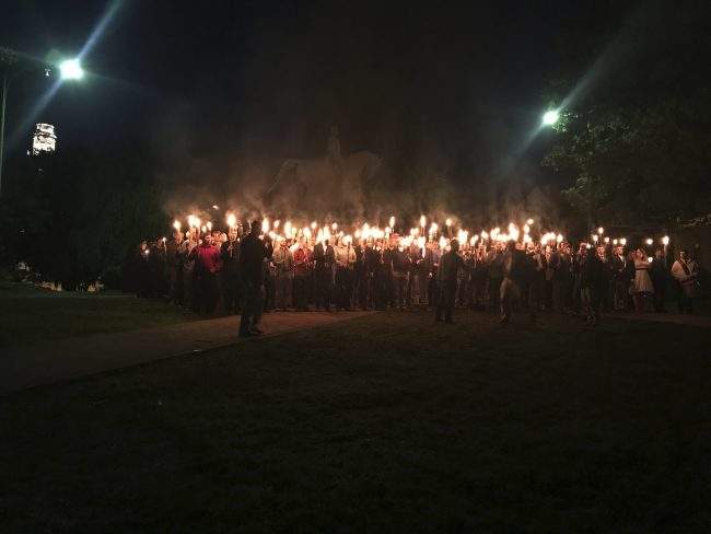 In this Saturday, May 13, 2017, photo, with a Gen. Robert E. Lee statue in the background,People gather at Lee Park in Charlottesville, Va., to protest the plans to remove the statue of Gen. Robert E. Lee, May 13, 2017.