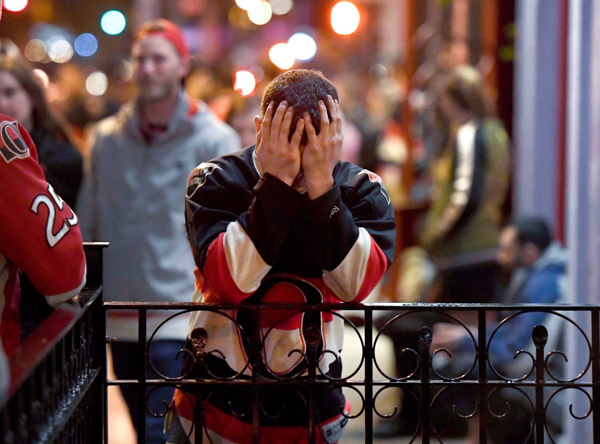 A Ottawa Senators fan puts his head in his hands after watching his team lose in double overtime during Game 7 of the Eastern Conference Final to the Pittsburgh Penguins, on Elgin Street's Sens Mile, in Ottawa on Thursday, May 25, 2017. 