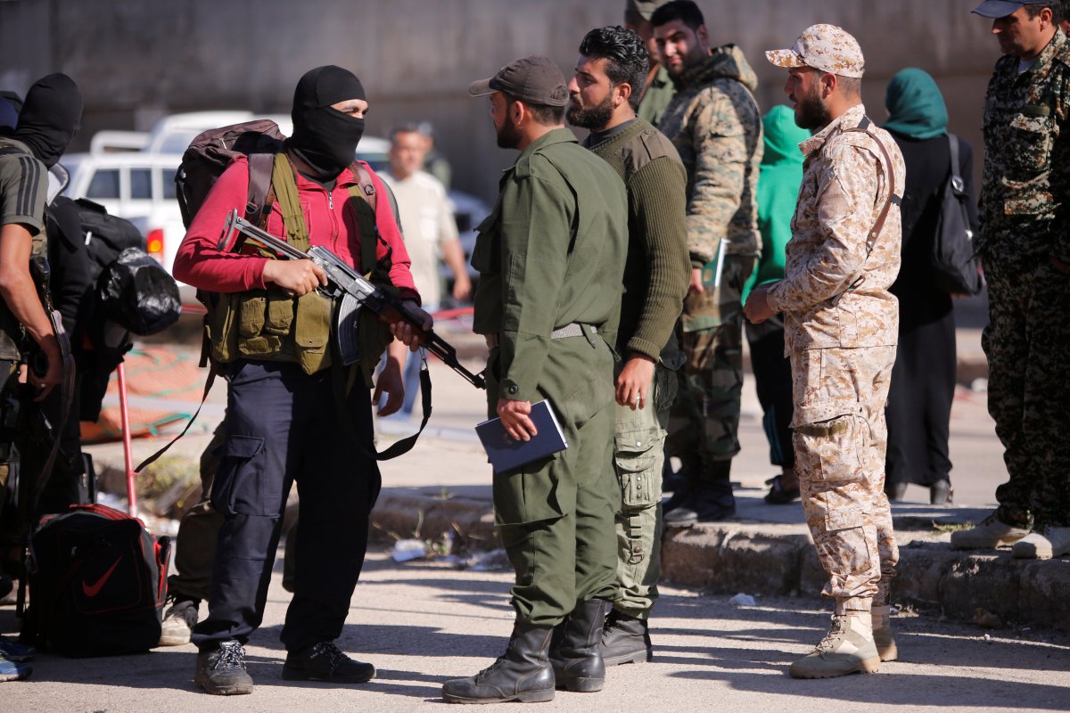 Rebel fighters (L) carry their weapons and belongings as they talk to Syrian army soldiers.